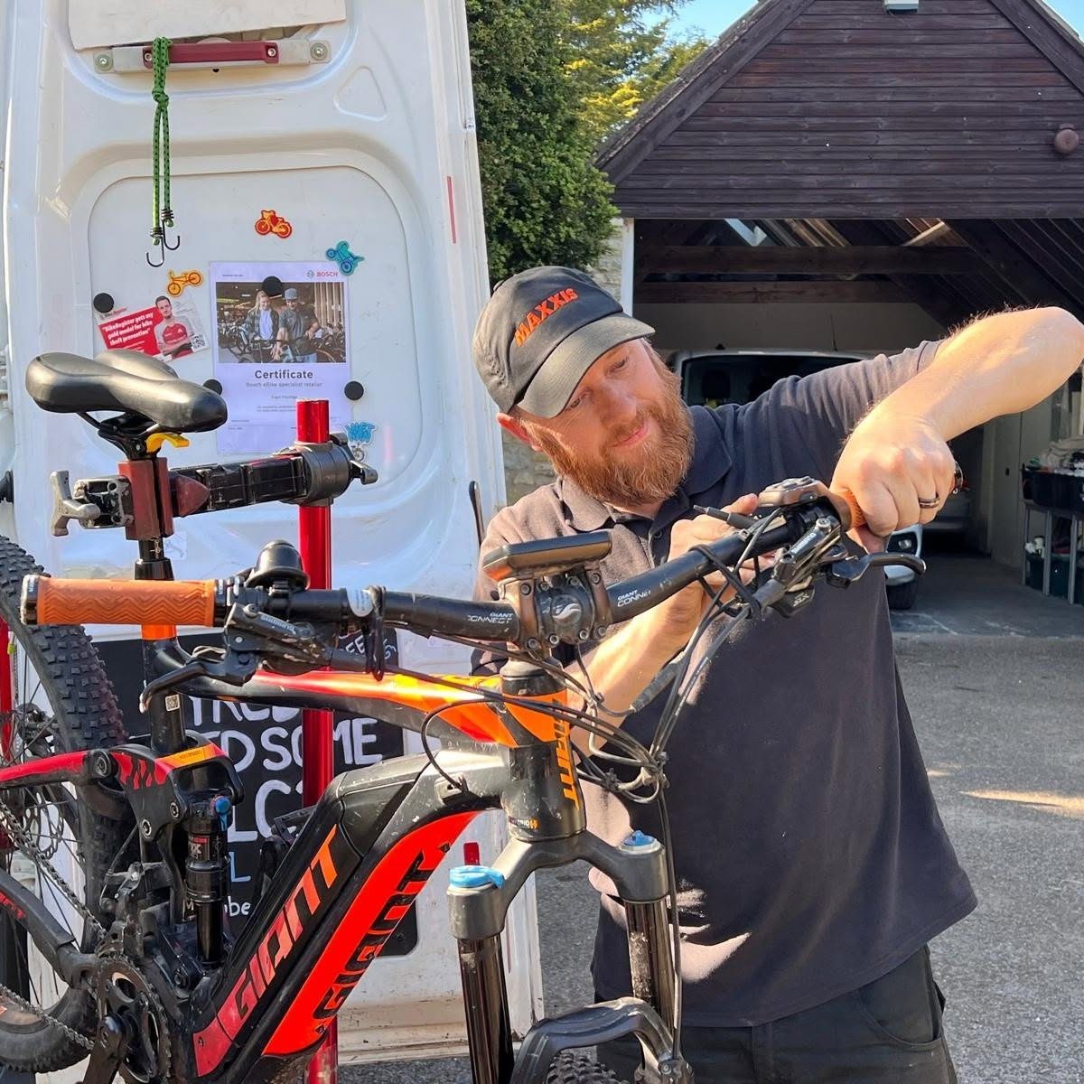 Bristol D&B bike ride bicycle mechanic fixing a child's tricycle next to a sign for a mobile cycle mechanic